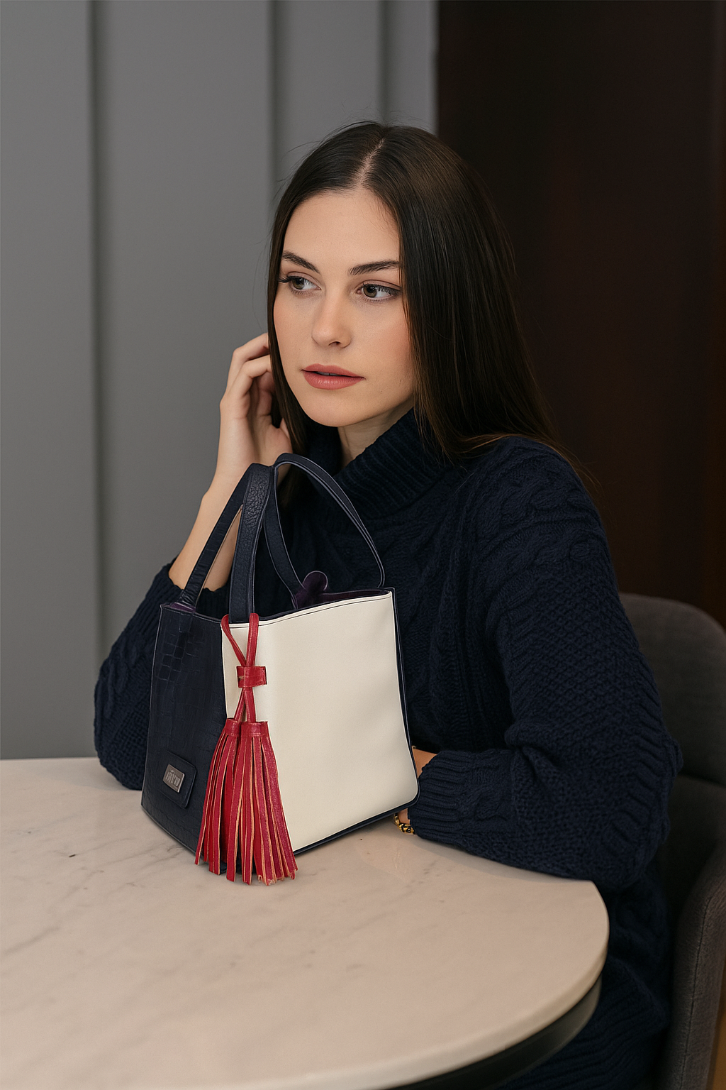 Mujer con bolso en cuero para mujer marca ZUHA colocado sobre  una mesa